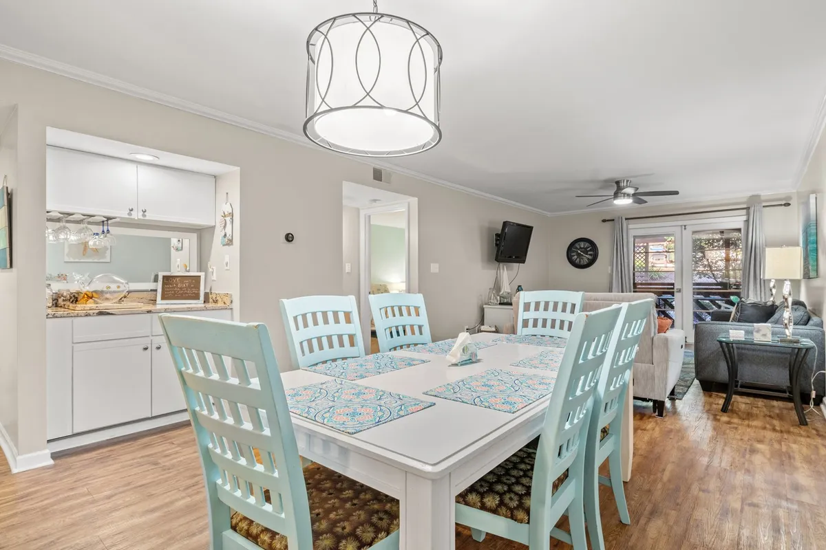 A cozy dining area is highlighted, featuring a central dining table beneath a stylish light fixture and adjacent to a sofa, all arranged in an open-concept living space perfect for shared meals and social gatherings.