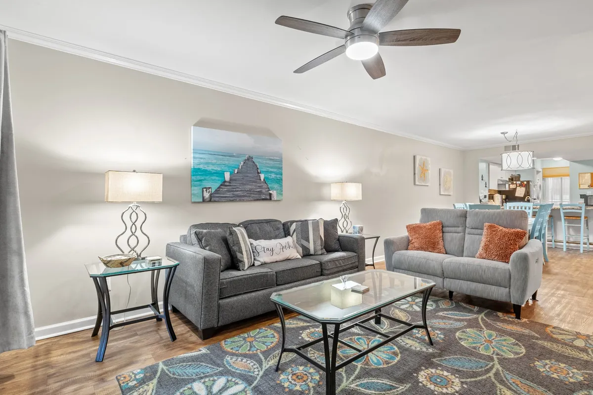 This image features a comfortable living room with a plush sofa adorned with decorative pillows, a coffee table set for relaxation or games, tasteful wall art, and soft lighting from lamps. The overall mood is welcoming and ideal for family gatherings or relaxing evenings.